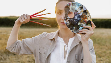 Vrouw kijkt door een gat in een pallet met verfkleuren, staand in een open veld bij zonsondergang, illustratie van zintuiglijk weten en ecstatologisch bewustzijn